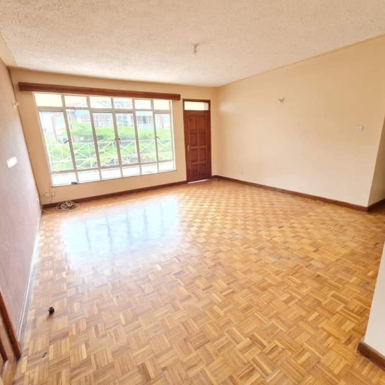 Bright family room with wood-effect flooring and multiple windows in a Riverside Drive apartment