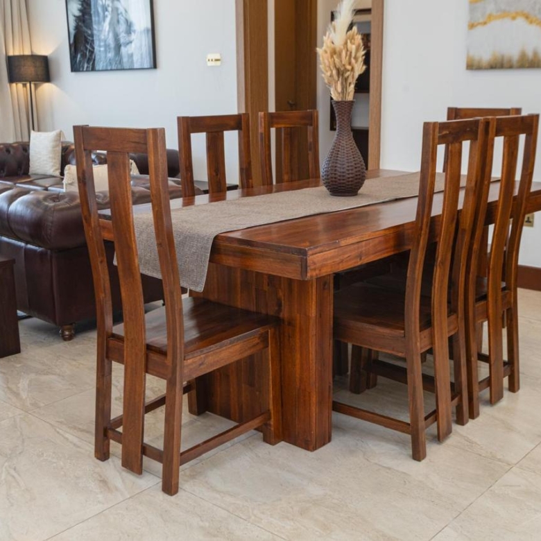 Wooden dining table and chairs in the living and dining area of a serviced Parklands apartment