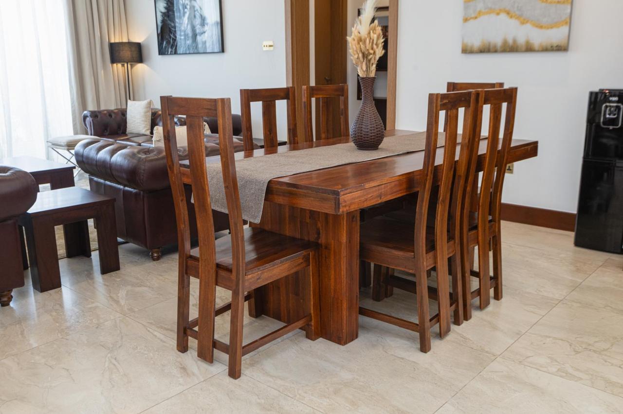 Wooden dining table and chairs in the living and dining area of a serviced Parklands apartment