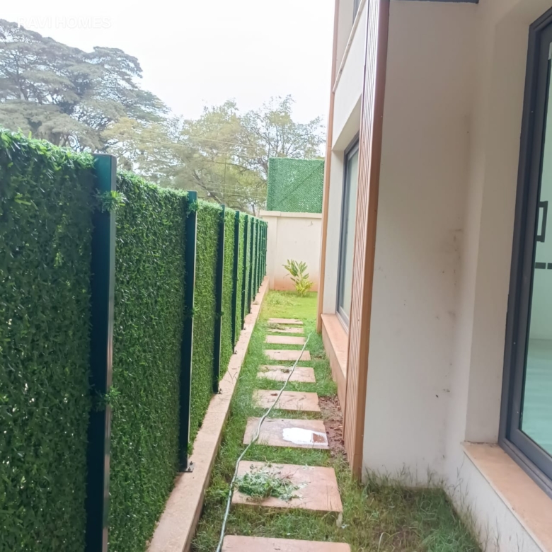 Garden Villas Lavington backyard pathway with stepping stones, green lawn, landscaped hedge fencing and modern villa exterior.