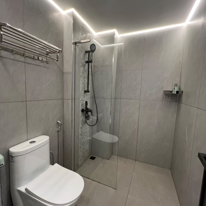 Longines Bay modern bathroom with glass shower enclosure, grey wall tiles and contemporary toilet.