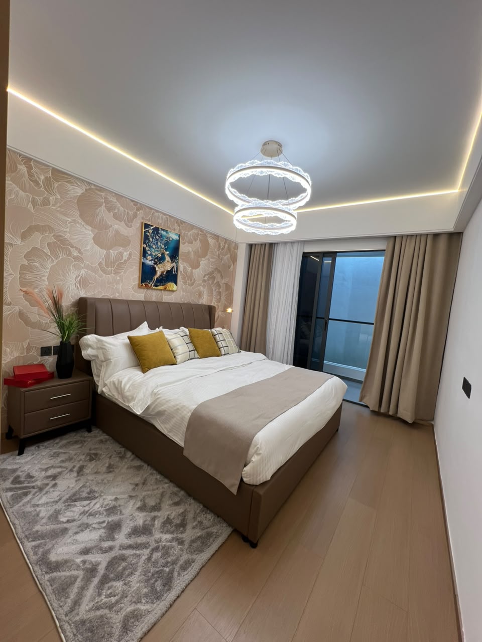 Longines Bay bedroom interior with upholstered bed, decorative wallpaper, chandelier and private balcony.
