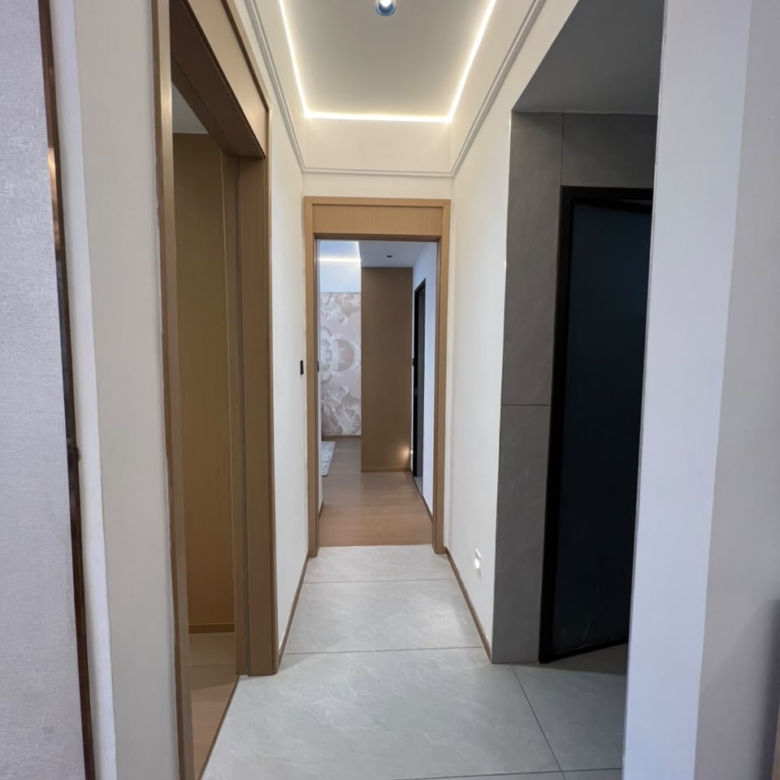 Longines Bay apartment hallway with grey tiled flooring, recessed ceiling lights and modern interior doors.