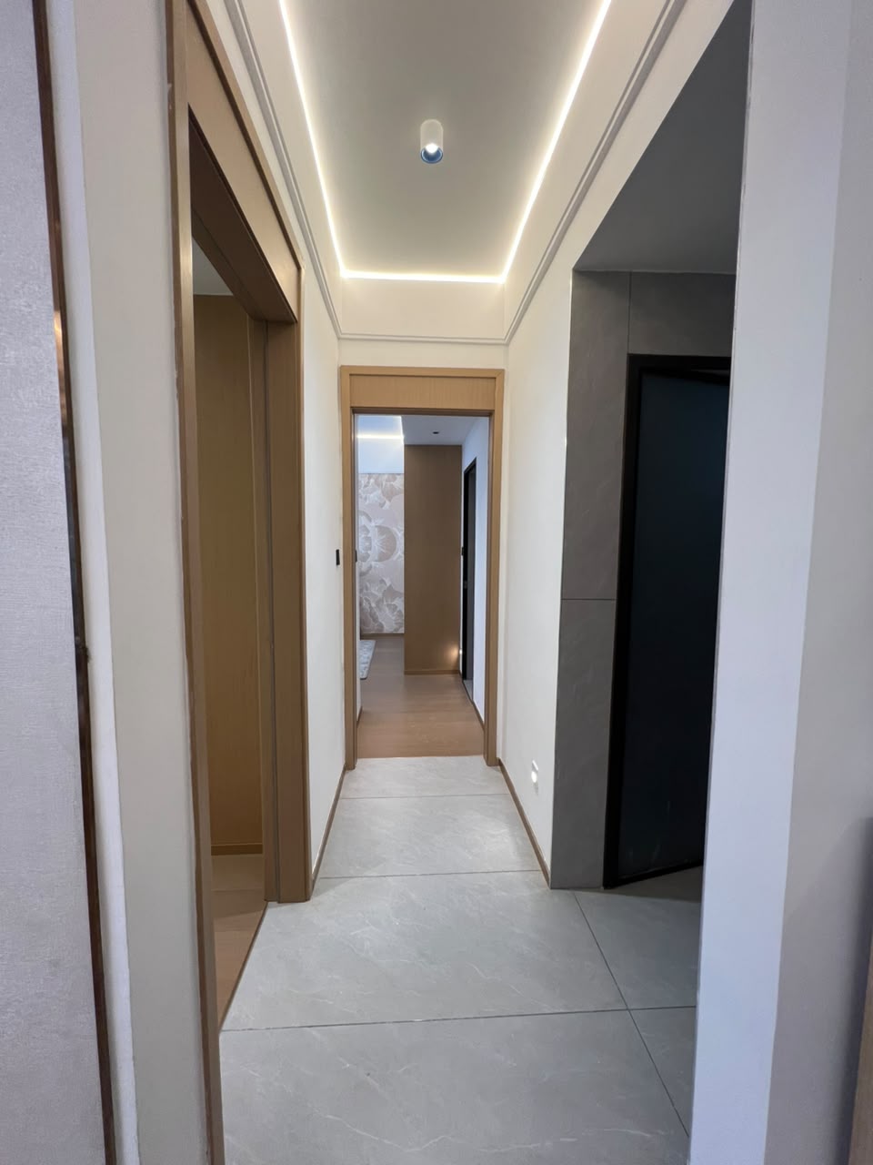 Longines Bay apartment hallway with grey tiled flooring, recessed ceiling lights and modern interior doors.
