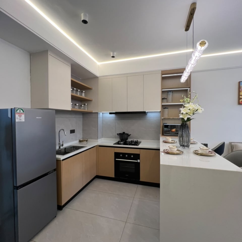 Longines Bay fitted kitchen with breakfast island, integrated oven, modern cabinetry and stainless steel refrigerator.