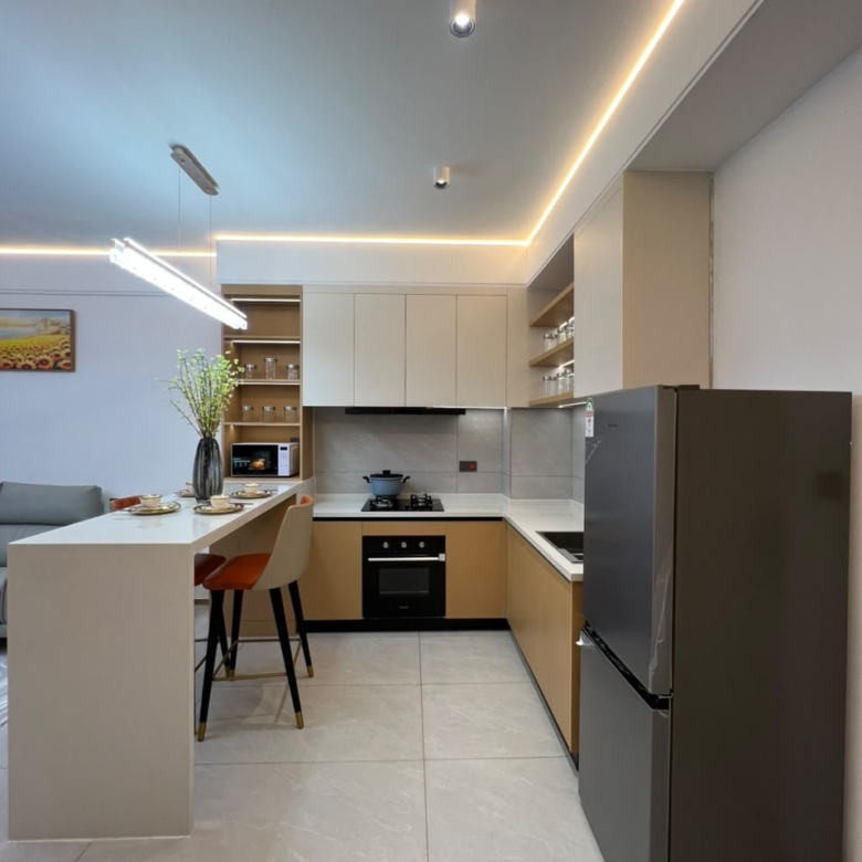 Longines Bay apartment kitchen with fitted cabinets, breakfast counter, built-in oven and modern appliances.