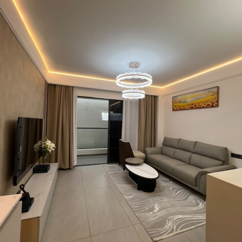 Longines Bay living room with modern sofa, decorative chandelier, tiled flooring and sliding balcony doors.