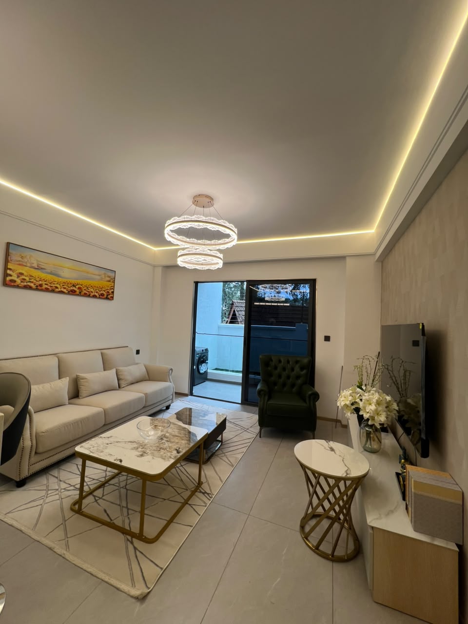 Longines Bay modern living room with upholstered sofa, television unit, decorative coffee tables and balcony access.