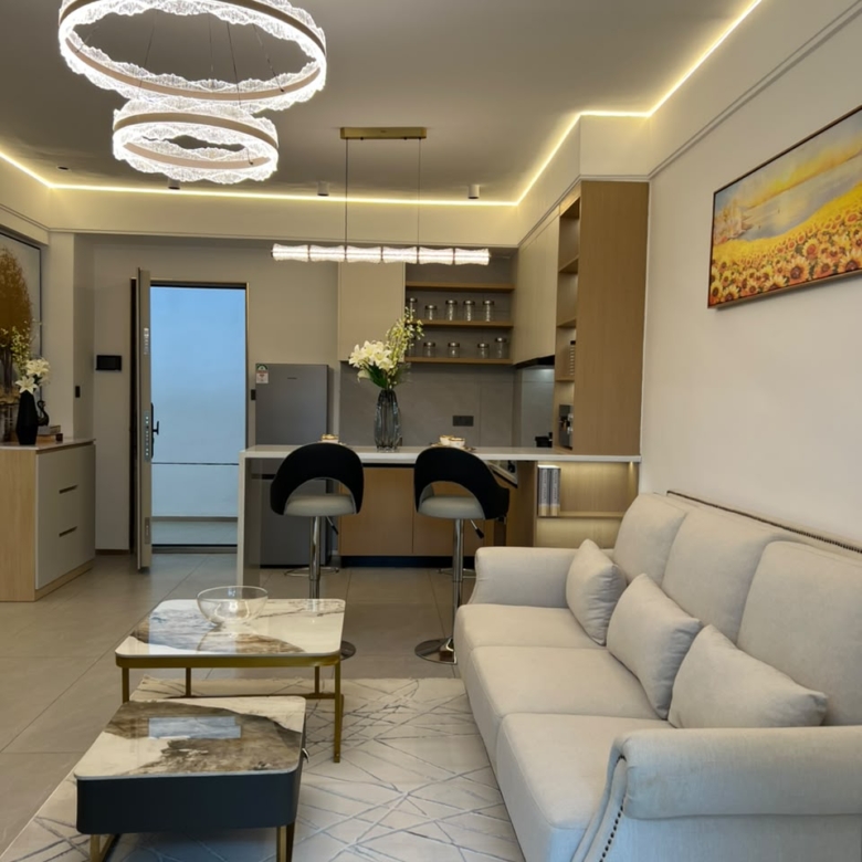Longines Bay open-plan living room with modern sofa, marble-style coffee tables, breakfast bar and decorative lighting.