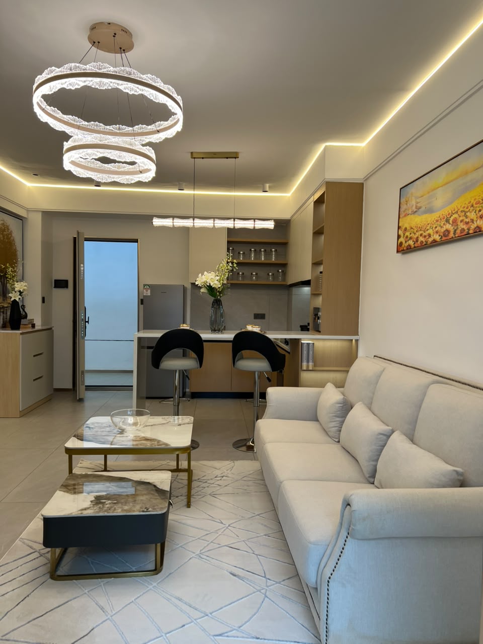 Longines Bay open-plan living room with modern sofa, marble-style coffee tables, breakfast bar and decorative lighting.