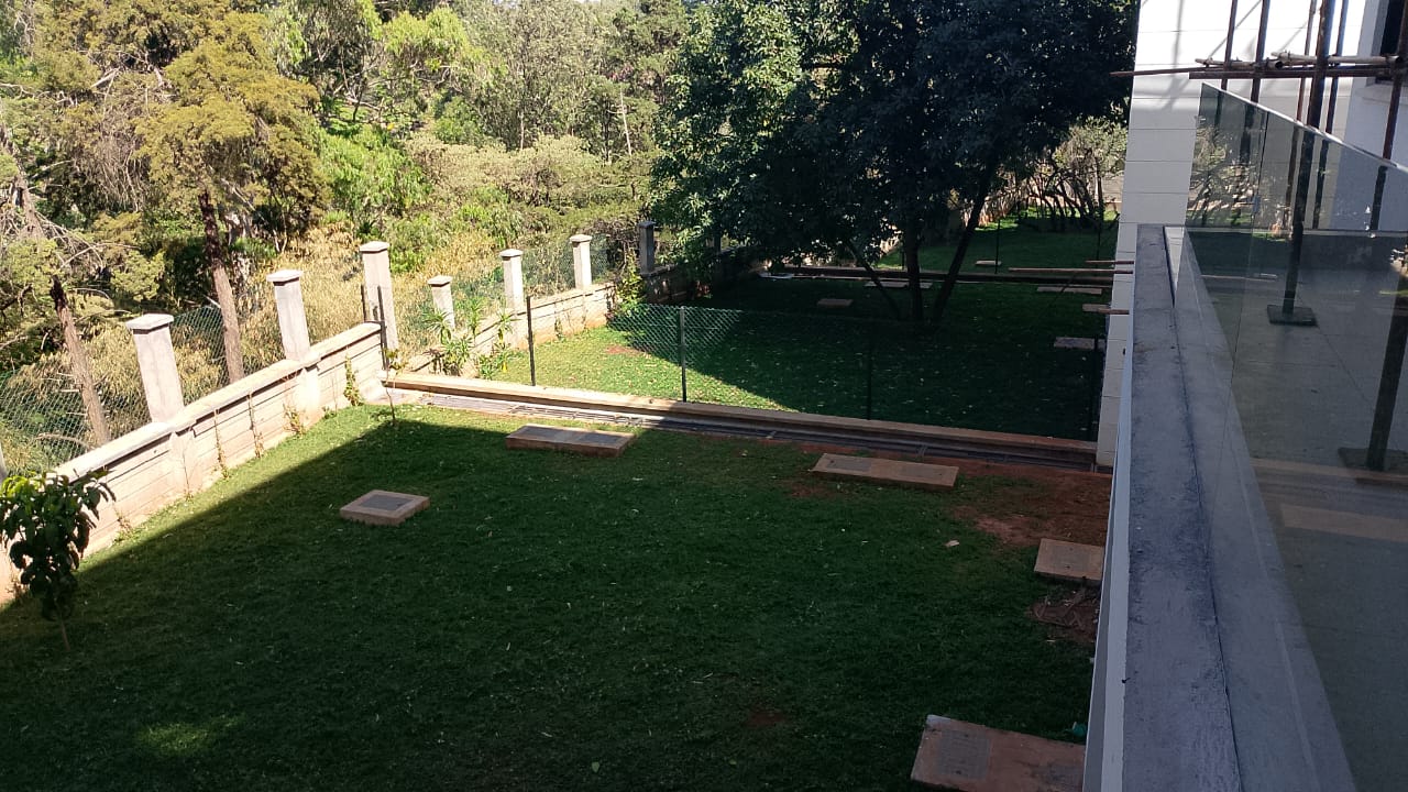 Radiant Villas private landscaped garden in Westlands Nairobi featuring green lawn, mature trees and perimeter fencing.